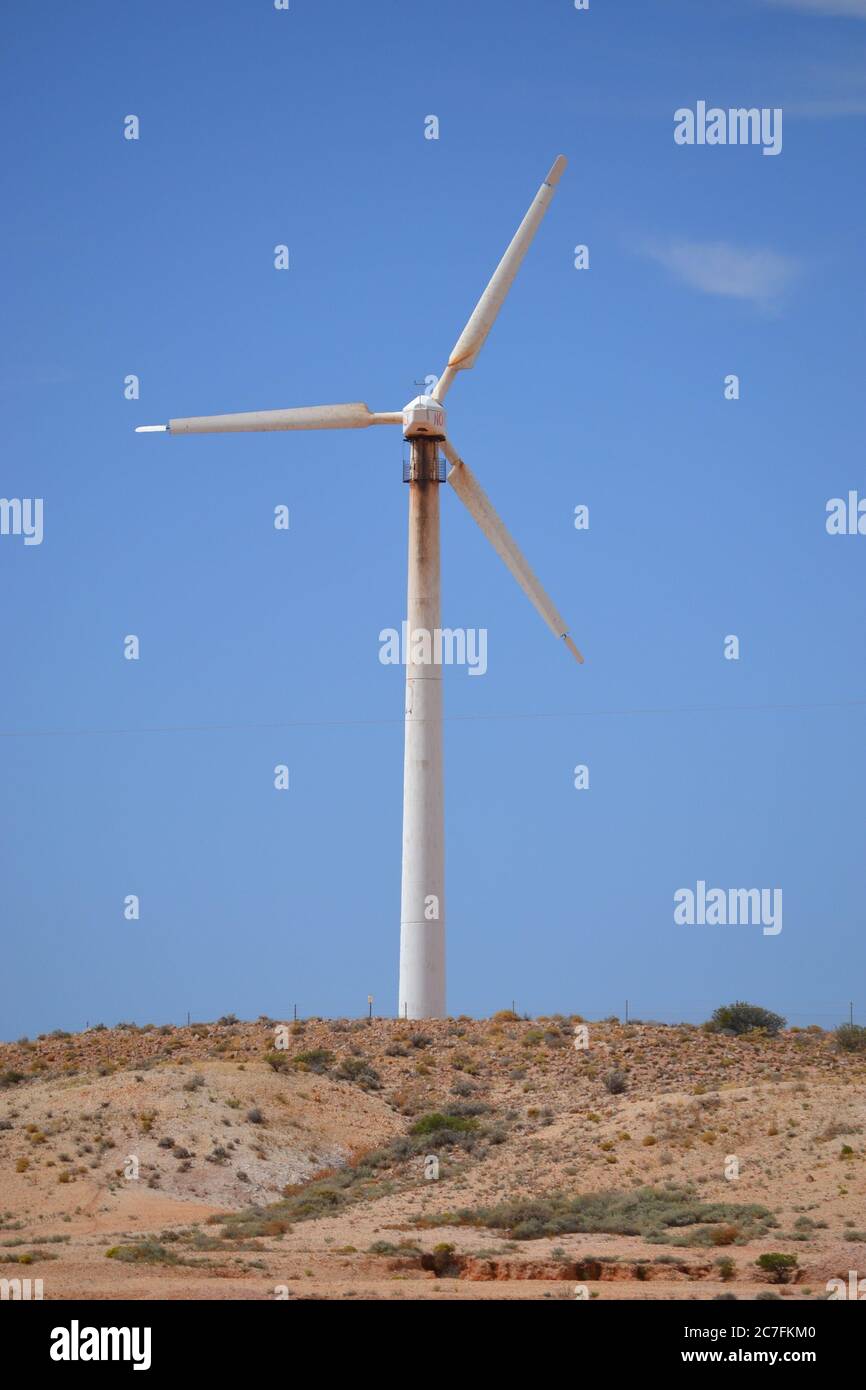 Wind turbine on a rocky hill in the Australian outback against a blue ...