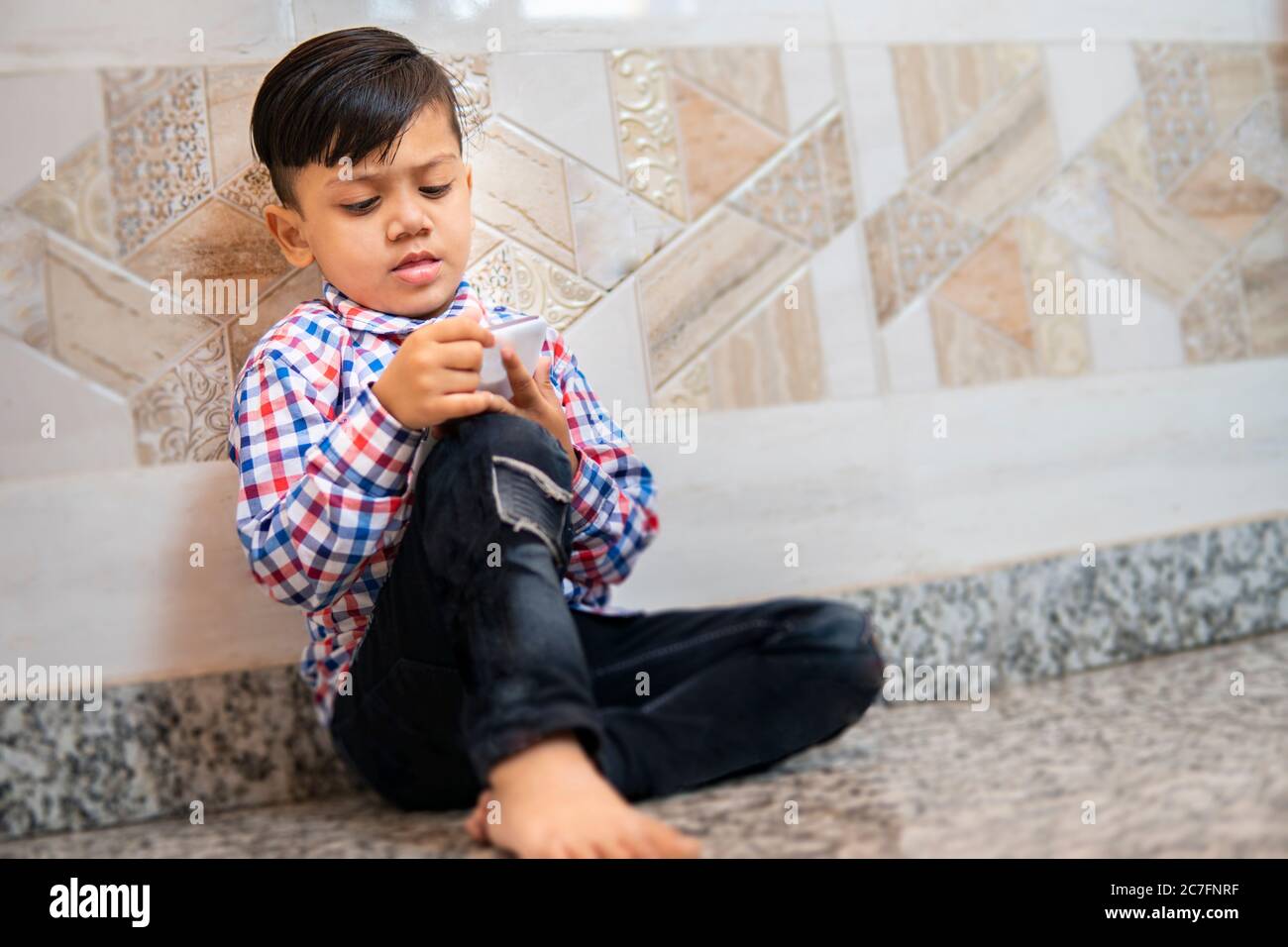 Indoor image of little boy using smartphone and playing video game in leisure time. Stock Photo