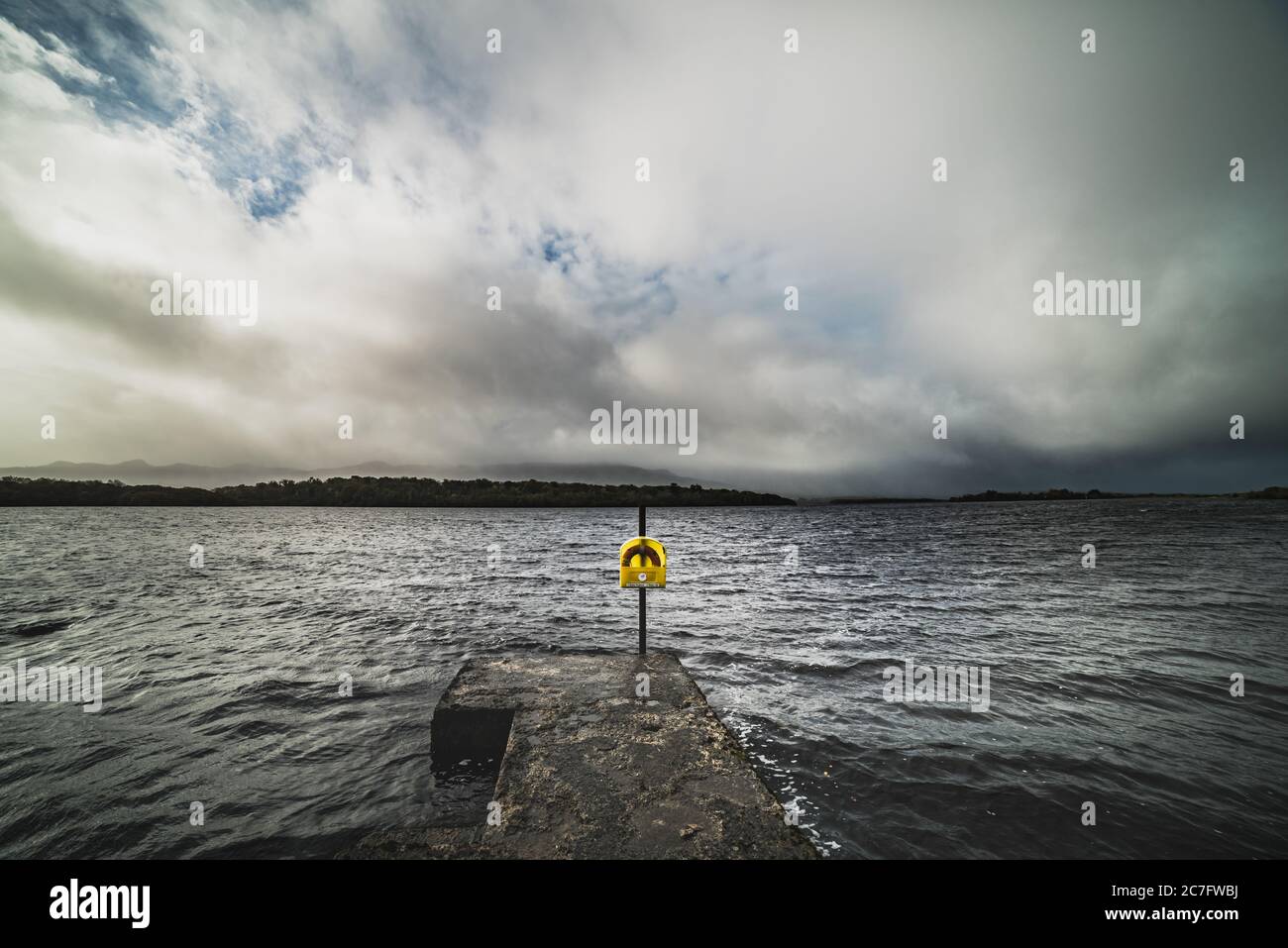 A ring buoy stands alone by Lough Melvin amid despair, helplessness and isolation. A life preserver by a stormy lake conveys grim and dramatic feeling Stock Photo