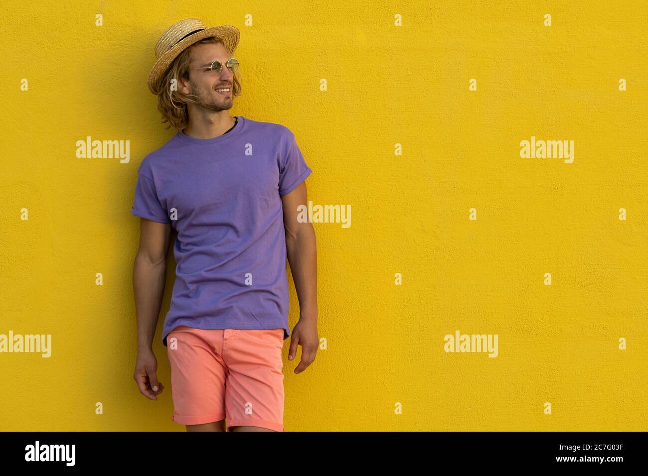 Young blond man with summer clothes, hat and sunglasses enjoying the summer Stock Photo