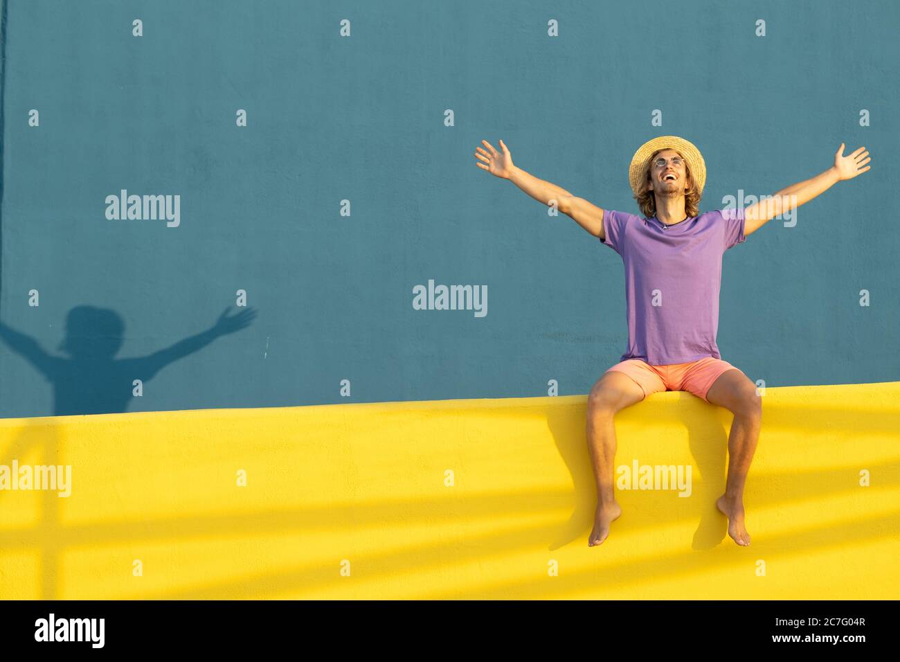 Young blond man with summer clothes, hat and sunglasses enjoying the summer Stock Photo