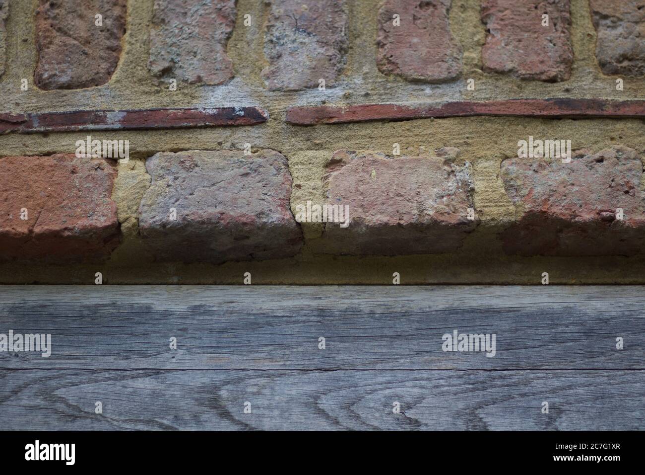 Background showing contrasting weathered wood with pointed old brickwork above Stock Photo