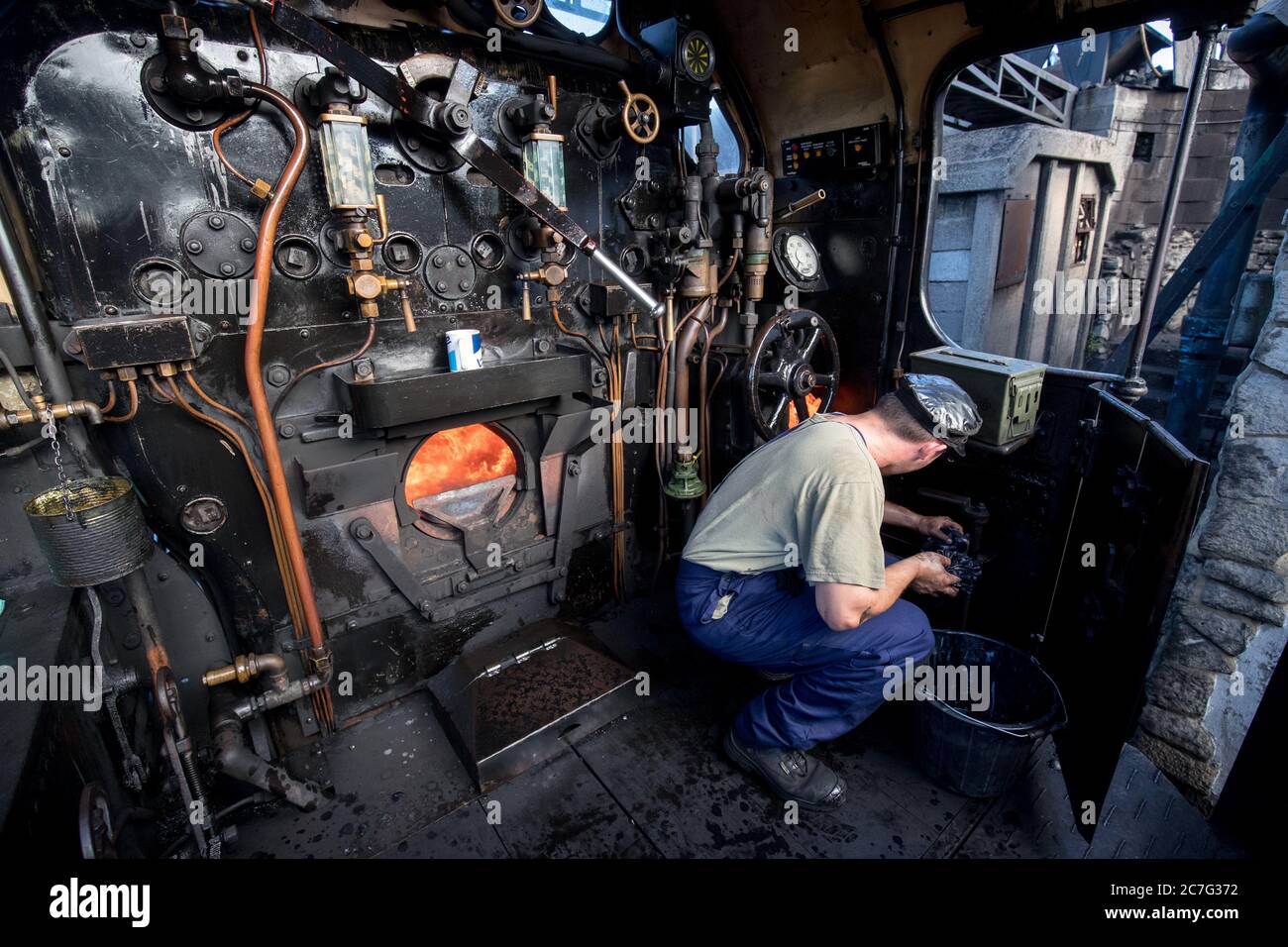 Fireman Alexander Atkins cleans the cab of the SR U Class steam locomotive No. 31806, as final preparations are made at the Swanage Railway ahead of the running of steam trains for the first time since the coronavirus lockdown in March. The heritage railway on the Isle of Purbeck, Dorset, will use steam engines again on Saturday with a non-stop service between Swanage and Norden stations with social distancing in place at stations and on trains and the wearing of face coverings. Stock Photo
