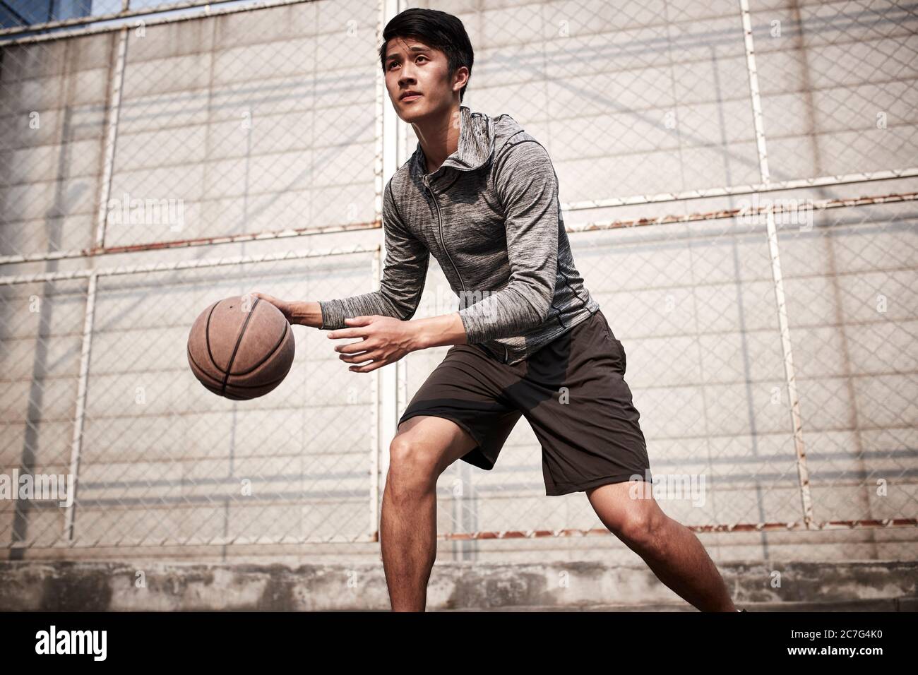 young asian male basketball player practice ball handling skills on outdoor court Stock Photo