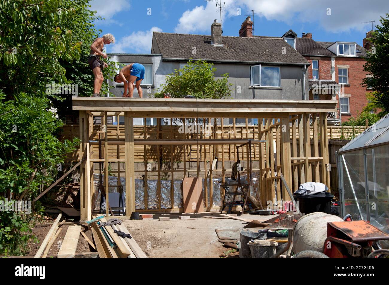 Two builders constructing the roof of a garden studio Stock Photo