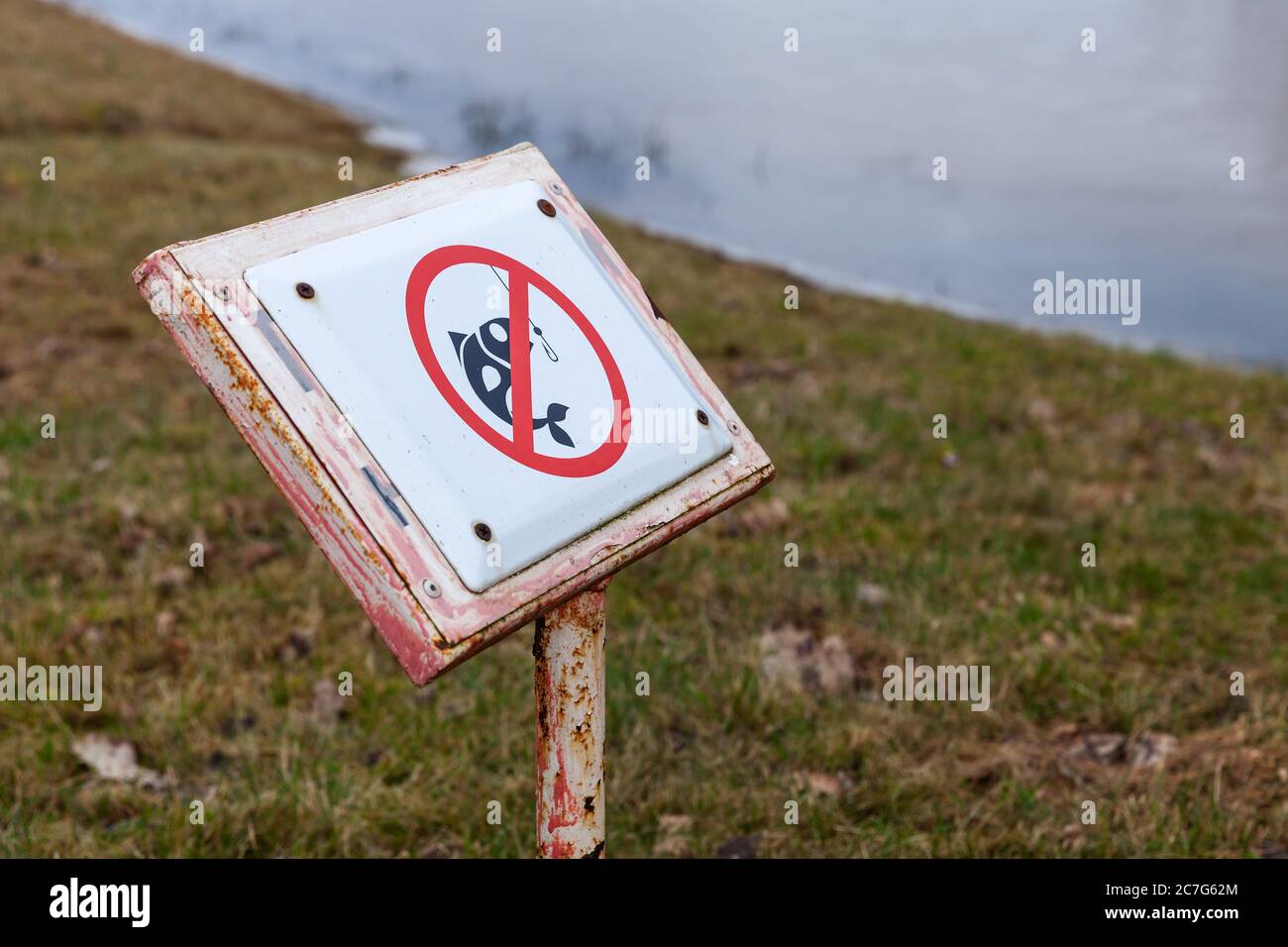 Fishing is not allowed here, caution sign on lake coast, close-up photo with selective focus Stock Photo