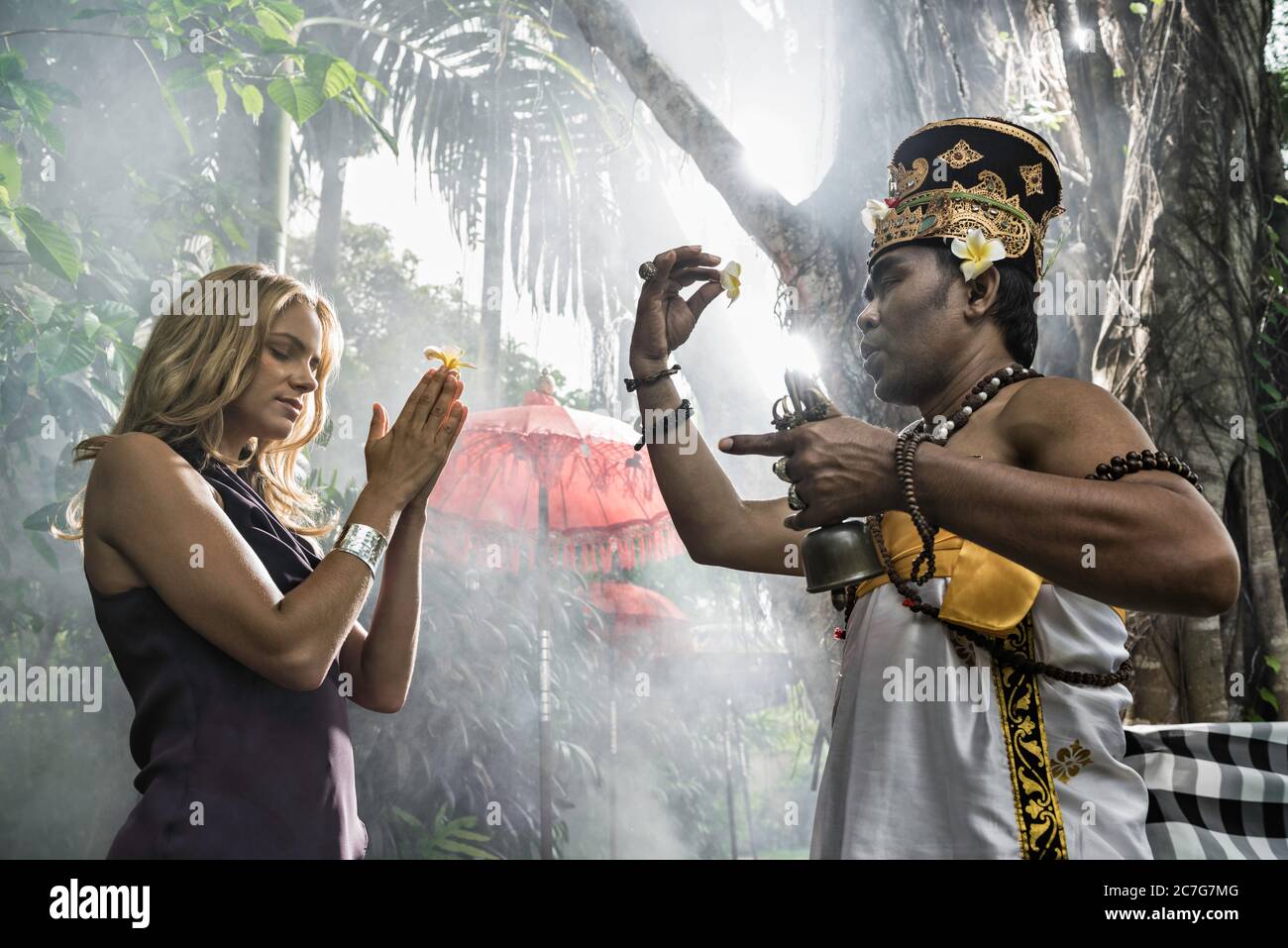 Asia, Indonesia, Bali, young, beautiful Caucasian woman wearing smart casual clothing, enjoying a local cultural experience, being blessed by a Baline Stock Photo