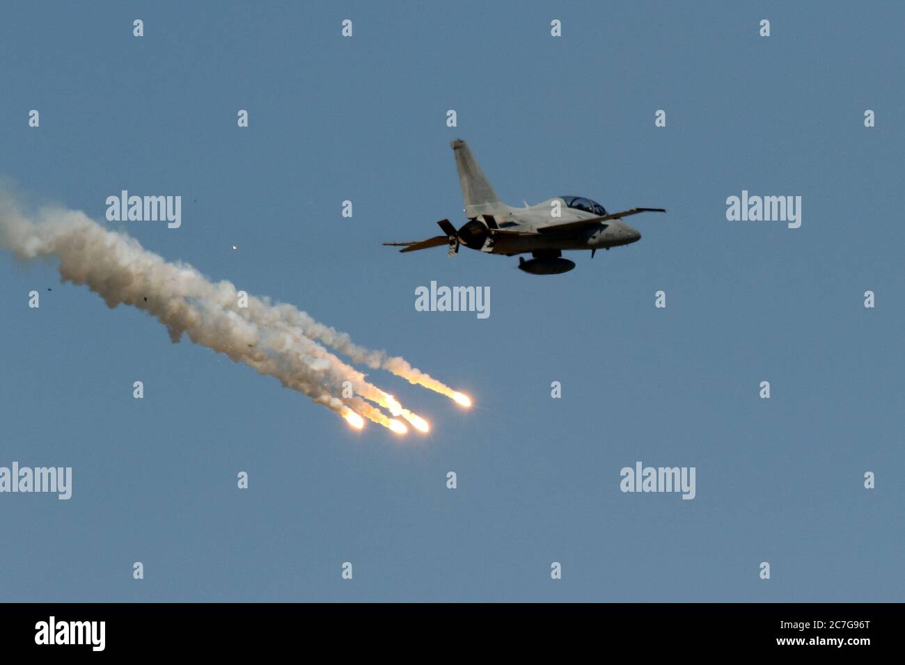 Jet aircraft flying in the sky and fireworks smoking below Stock Photo ...