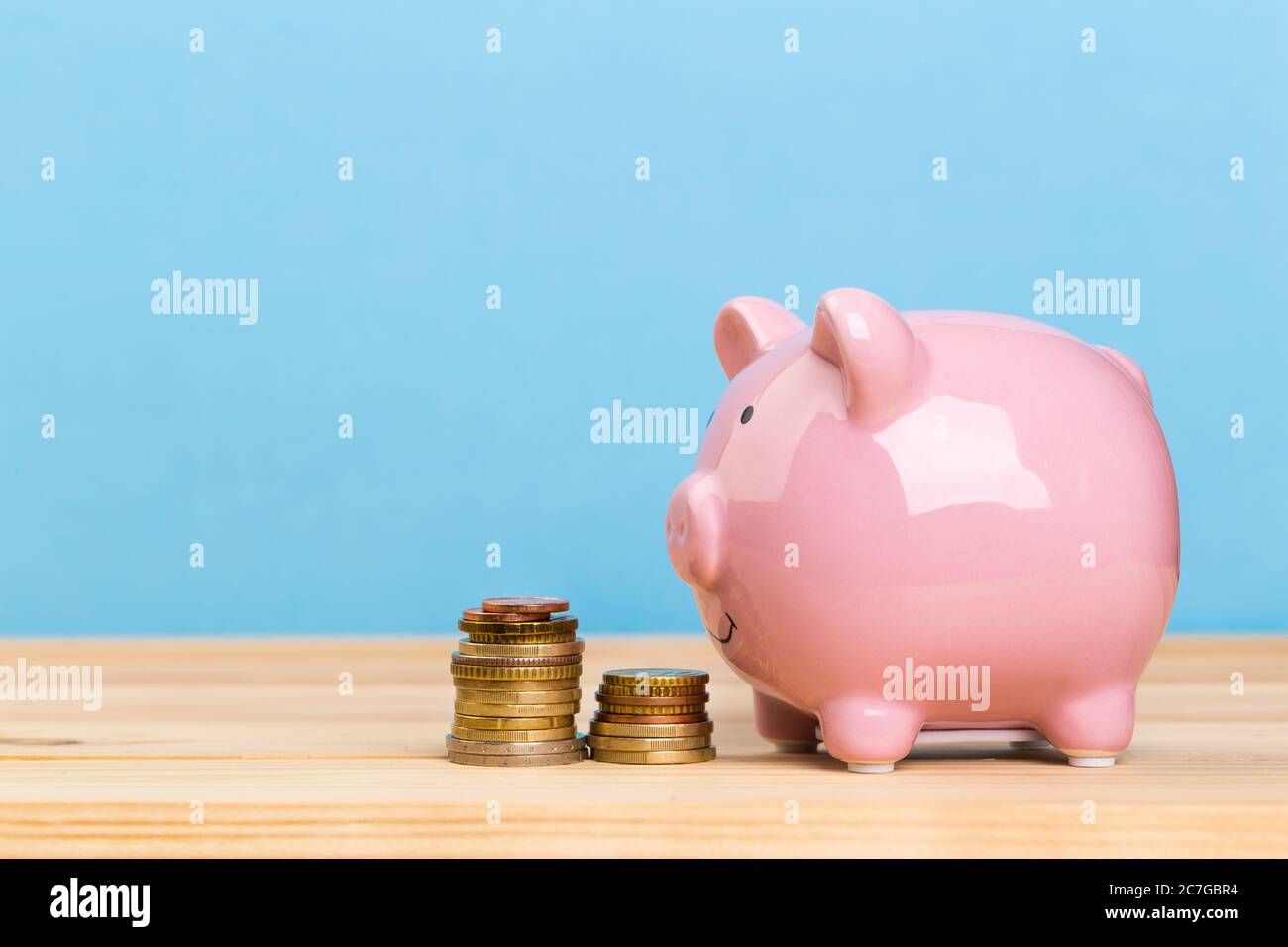 Pink piggy bank on wooden table and blue background. The concept of ...