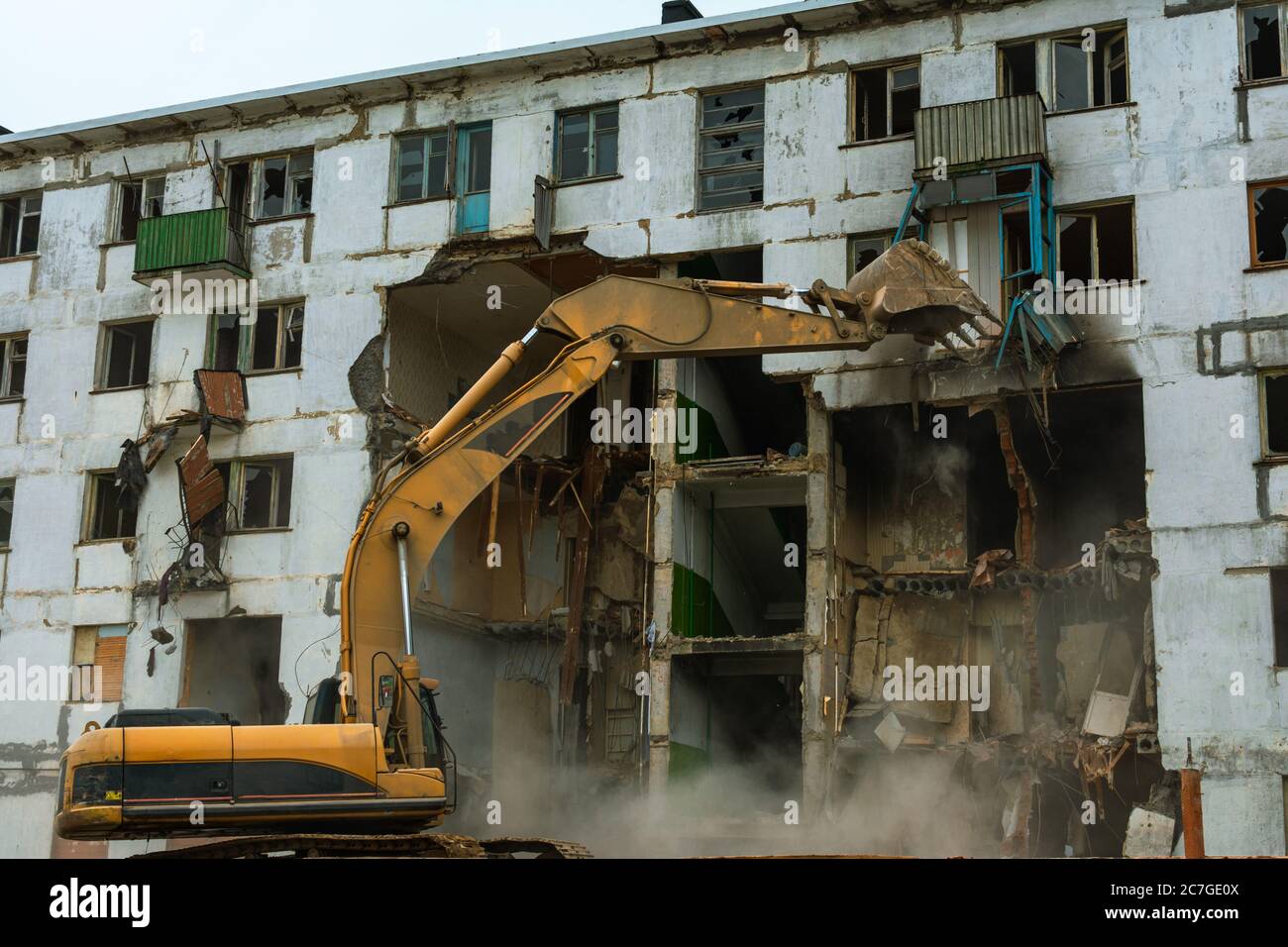 Demolition of a five-story apartment building recognized as emergency housing, excavator bucket destroys the balcony Stock Photo