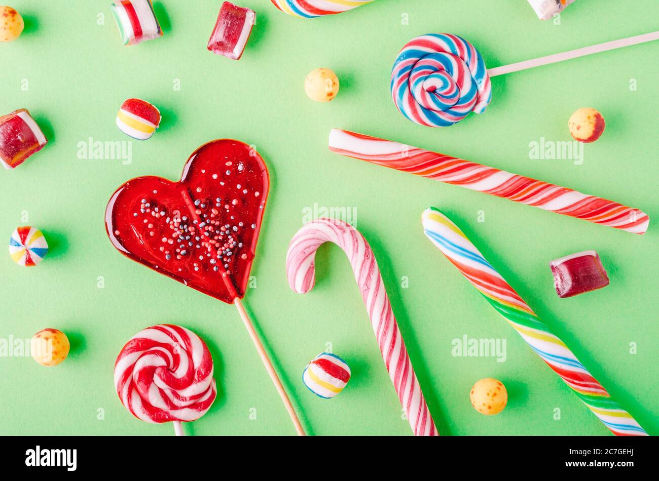 Closeup shot of candy canes and other candies on a green background ...