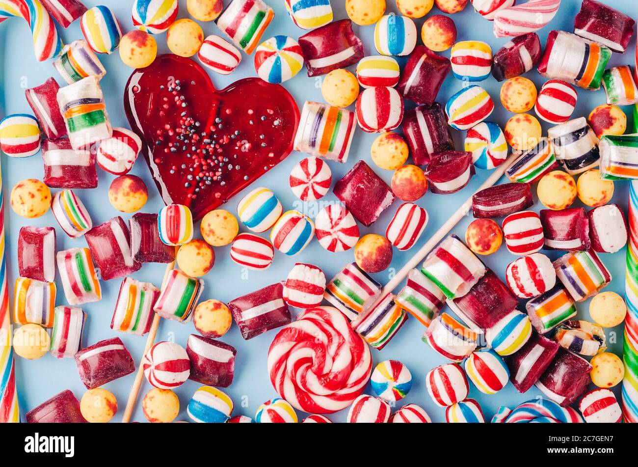 High angle shot of colorful candies and a heart-shaped lollipop