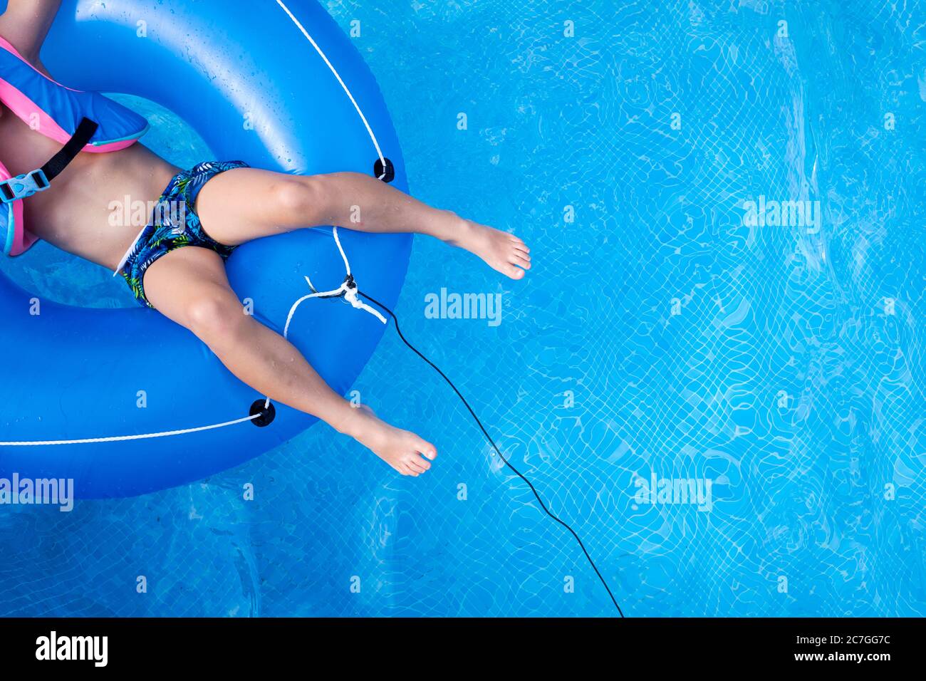 Boy floating in a pool with float playing while learning to swim Stock