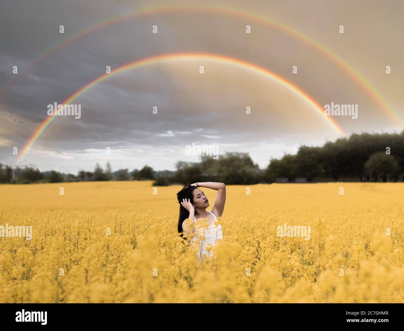 Young girl standing in the large field of yellow flowers and the double ...