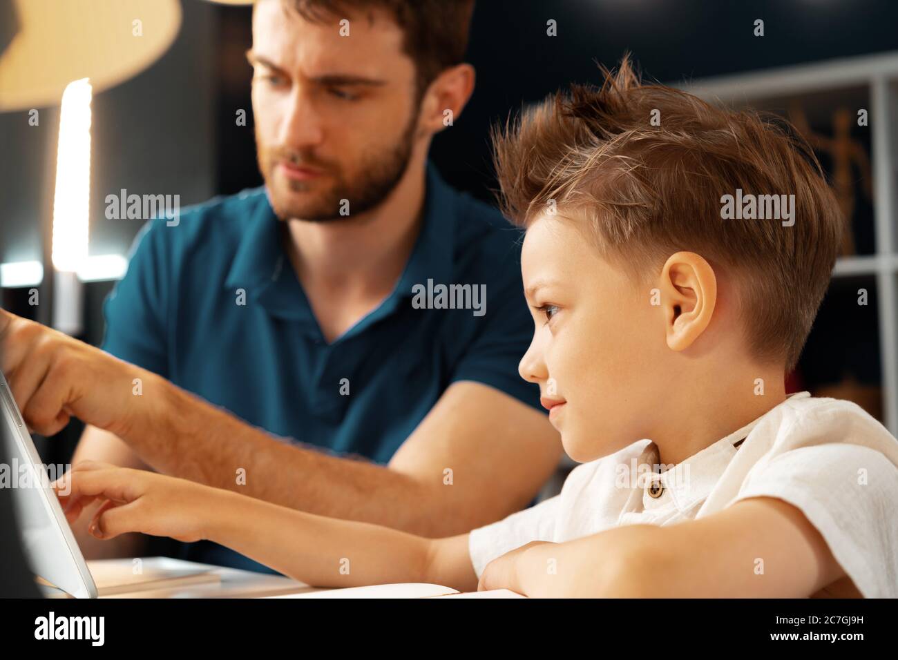 Young boy sitting with his father at the table and using laptop Stock ...