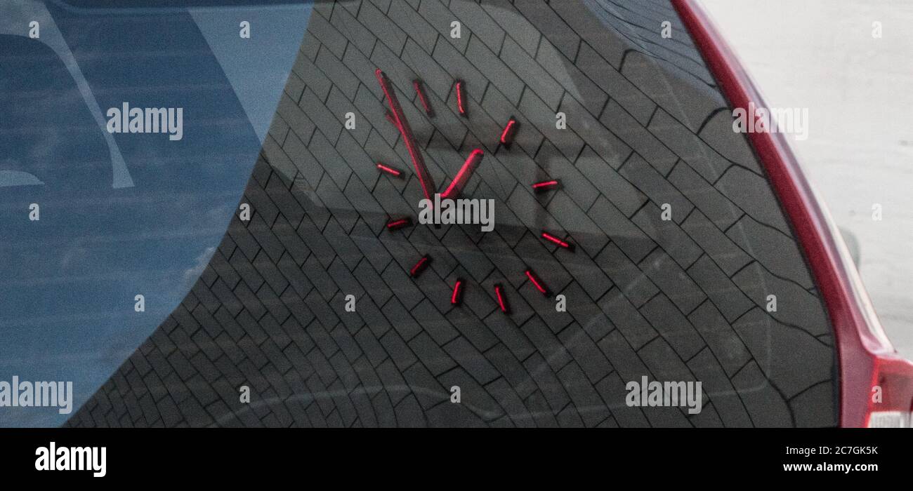 Red clock on a brick wall reflected on a car window Stock Photo