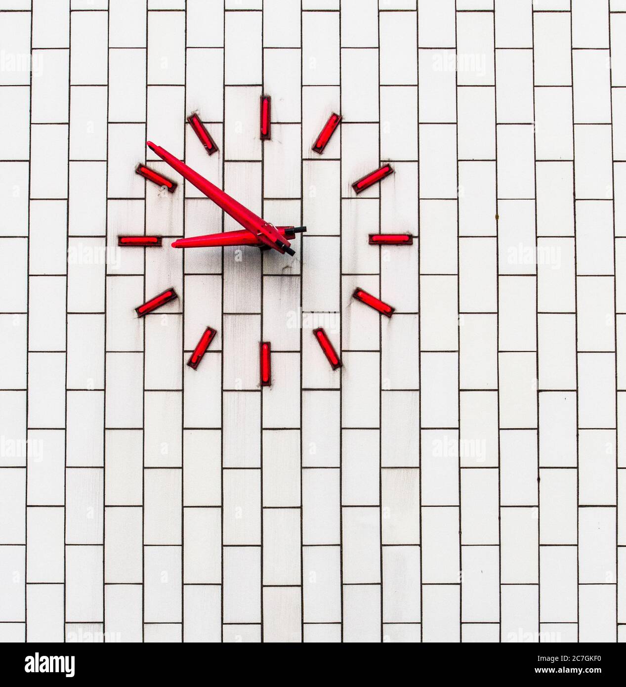 Red clock on a white brick wall Stock Photo