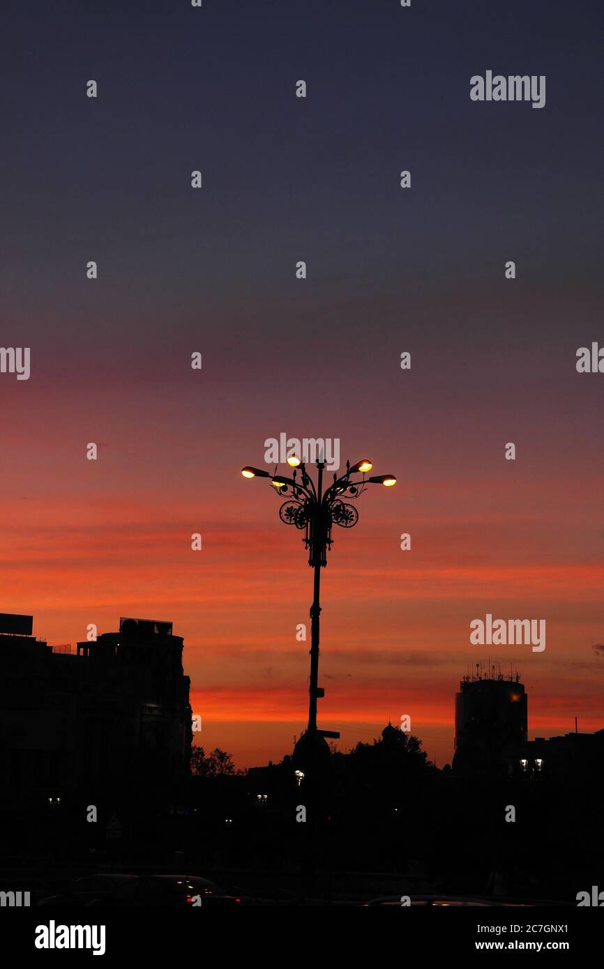 a lamp post and city silhouette in sunset sky Stock Photo - Alamy