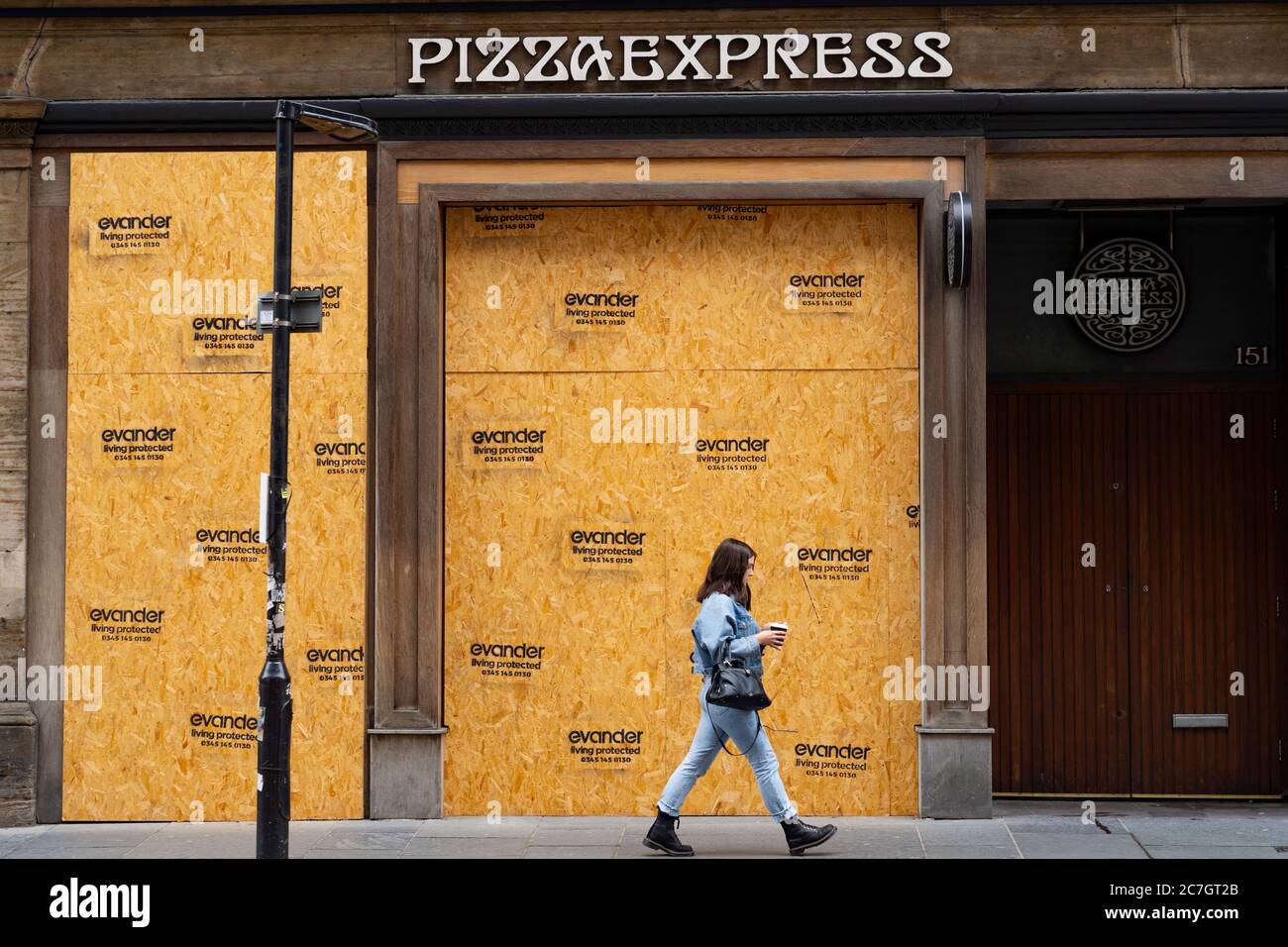 Glasgow, Scotland, UK. 17 July, 2020.  Images from Glasgow city centre as covid-19 restrictions are relaxed and  the public are out and about shopping and at work. Pictured; woman walks past closed and boarded up Pizza Express restaurant. Iain Masterton/Alamy Live News Stock Photo