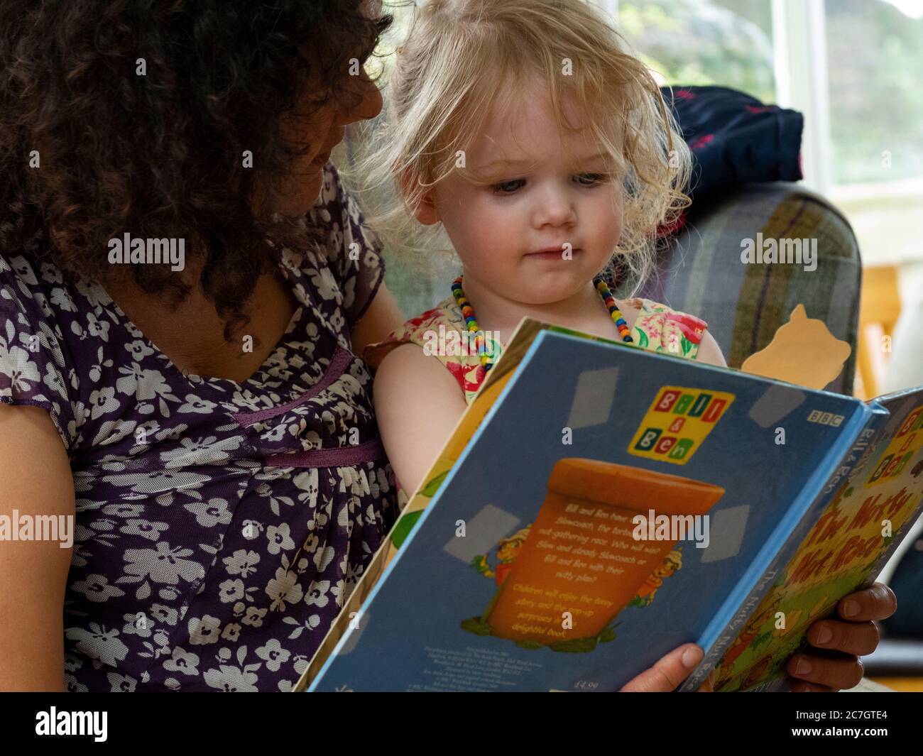 Toddler and granny reading a book together, UK Stock Photo