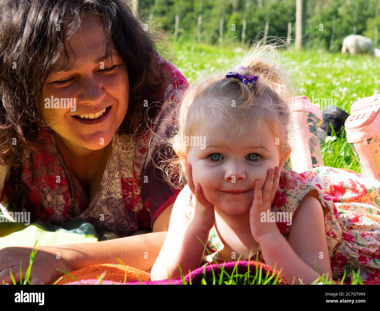 Toddler and granny lying on the grass, UK Stock Photo