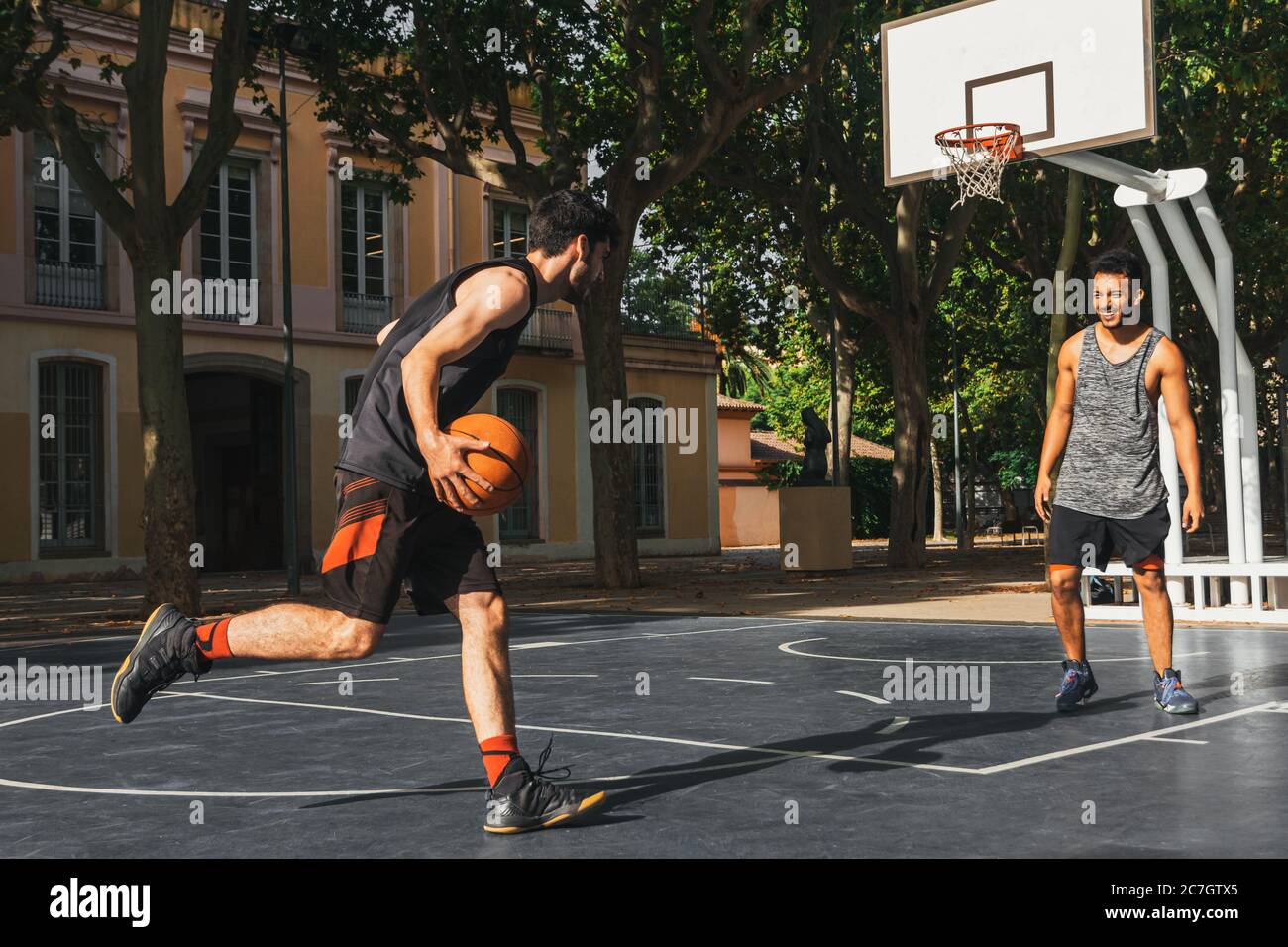 two young men play basketball outdoors Stock Photo