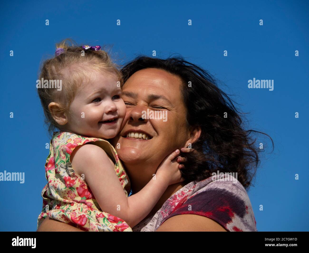 Toddler tightly cuddling granny, UK Stock Photo