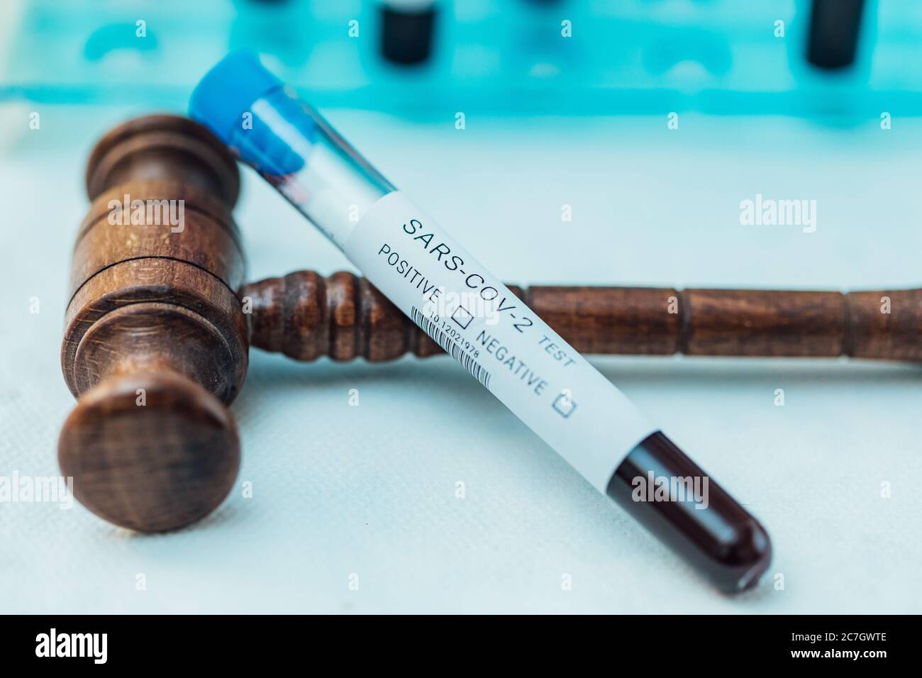 Test tube with blood to do COIVD test supported by judge's gavel Stock Photo