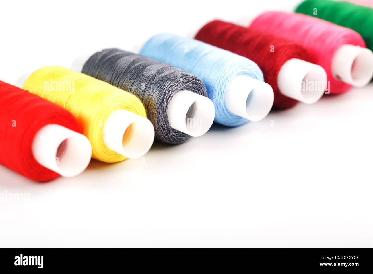 Sewing threads of different colors on reels on a white background. Free ...
