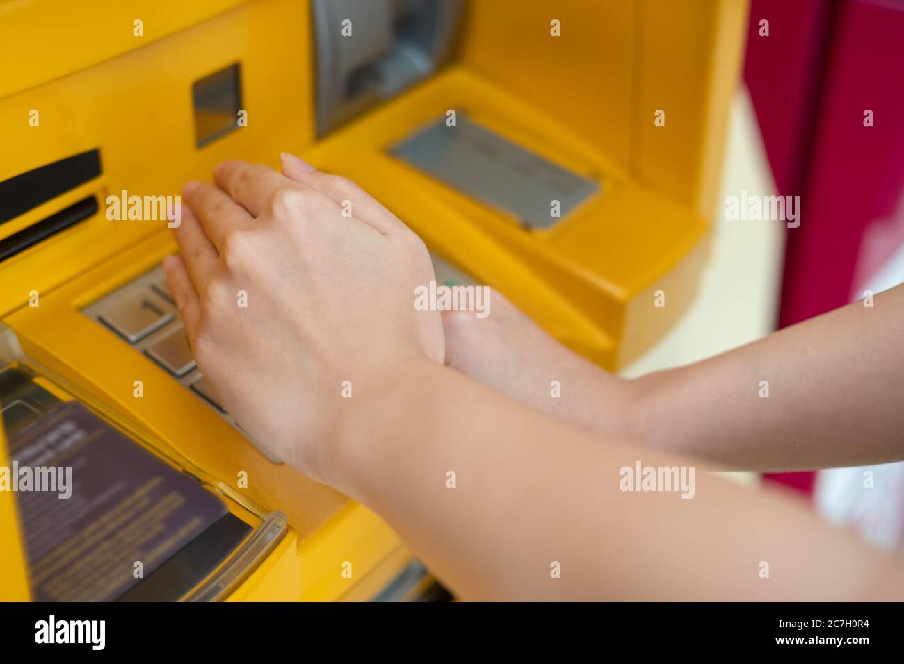 Woman hiding password by hand while input ATM password for withdrawal Stock Photo