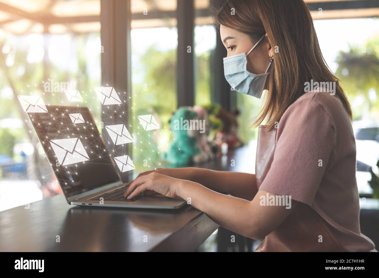 Asian woman wearing protection mask working on laptop in coffee shop ...