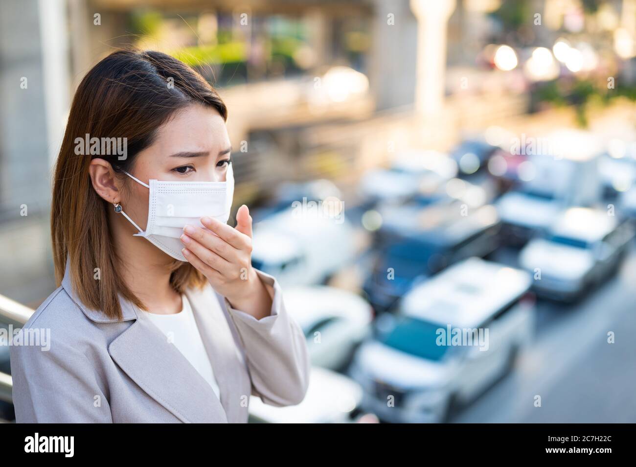 Young business woman wearing surgical mask and couging while walking in public in Coronavirus or COVID-19 spreading situation Stock Photo