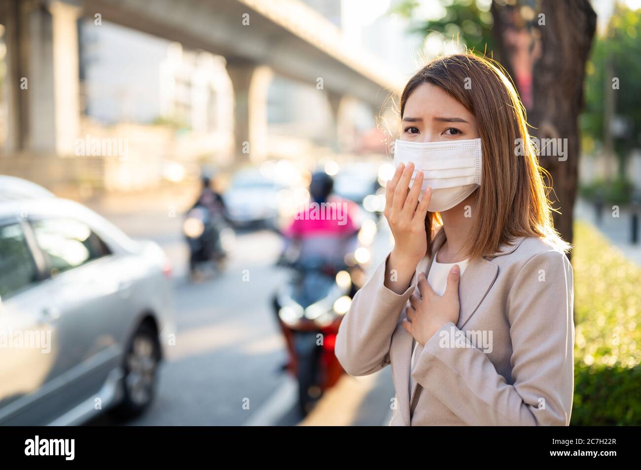 Young business woman wearing surgical mask and couging while walking in public in Coronavirus or COVID-19 spreading situation Stock Photo