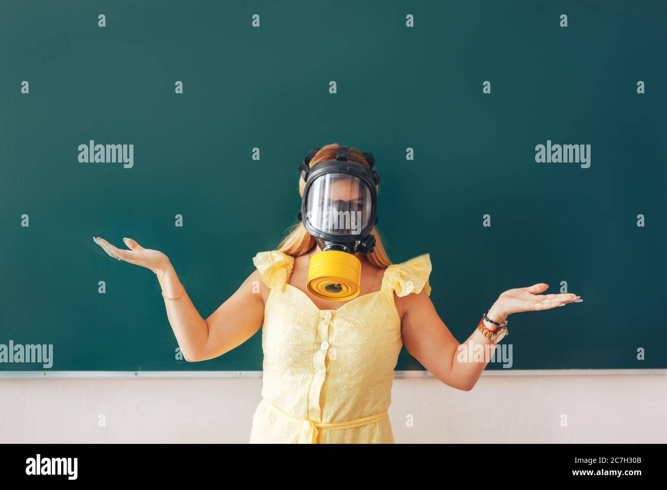 Young teacher in a medical mask holding a pointer in her hand and ...