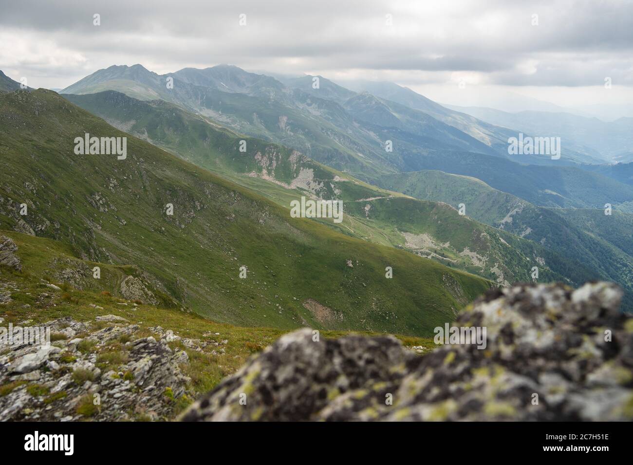 Landscape of hills covered in greenery with rocky mountains under a ...