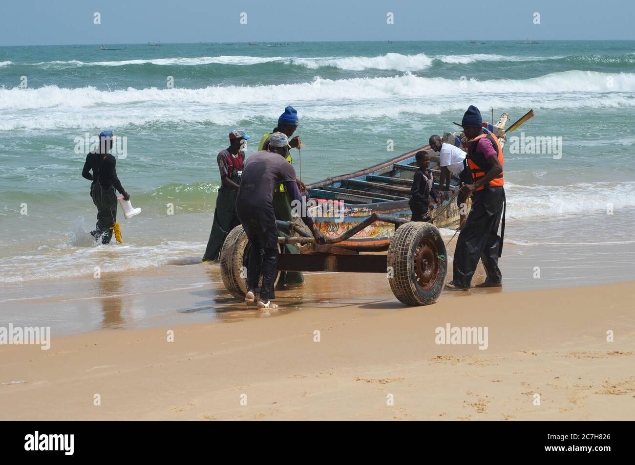 Artisanal fishermen pushing pirogues out of the water in Lompoul, Senegal Stock Photo