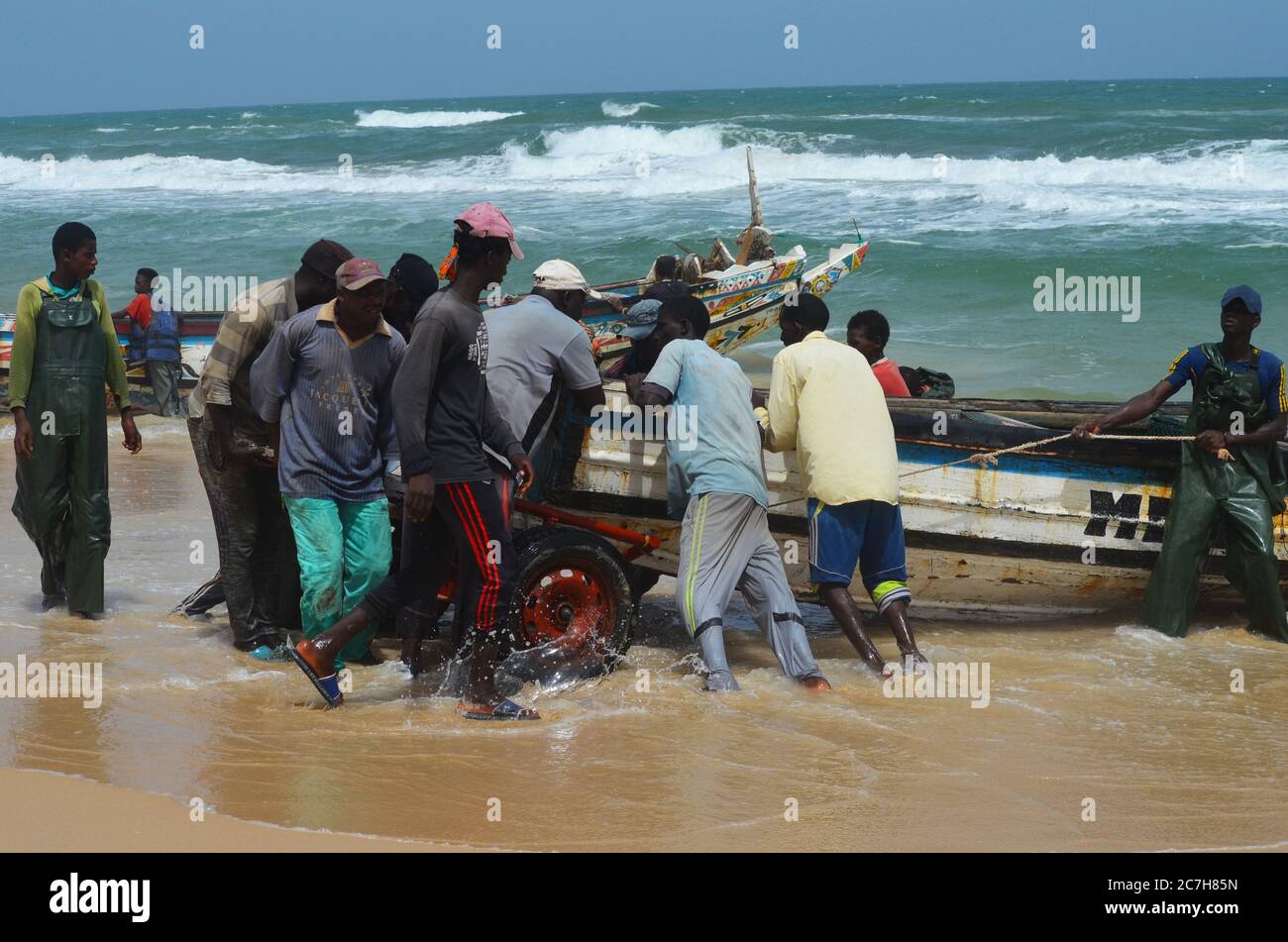 Artisanal fishermen pushing pirogues out of the water in Lompoul, Senegal Stock Photo