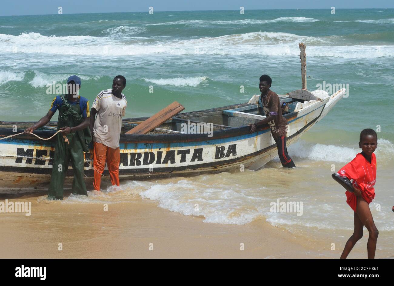 Artisanal fishermen pushing pirogues out of the water in Lompoul, Senegal Stock Photo