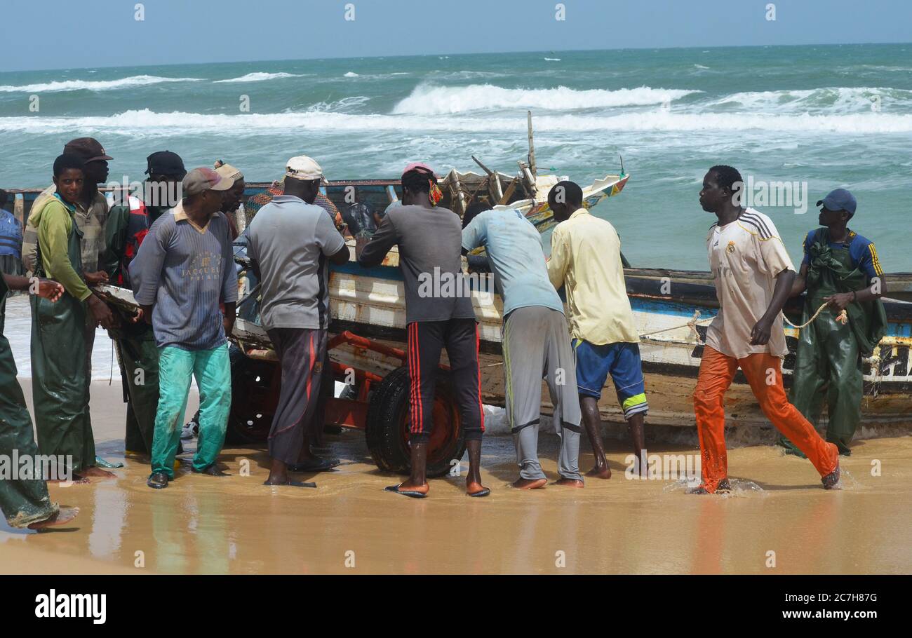 Artisanal fishermen pushing pirogues out of the water in Lompoul, Senegal Stock Photo