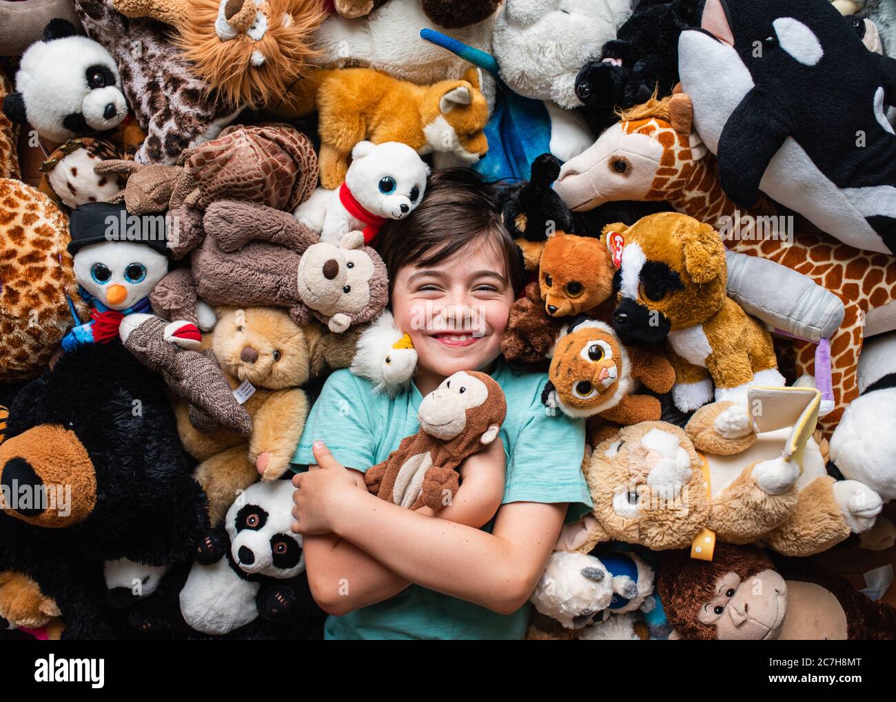 https://c8.alamy.com/comp/2C7H8MT/happy-young-boy-surrounded-by-his-stuffed-animals-shot-from-above-2C7H8MT.jpg