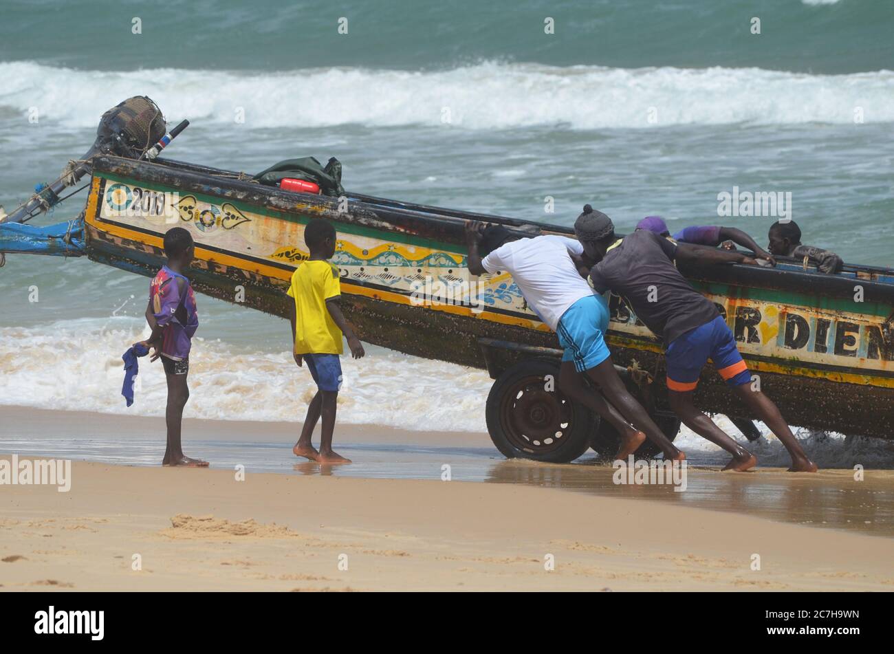 Artisanal fishermen pushing pirogues out of the water in Lompoul, Senegal Stock Photo