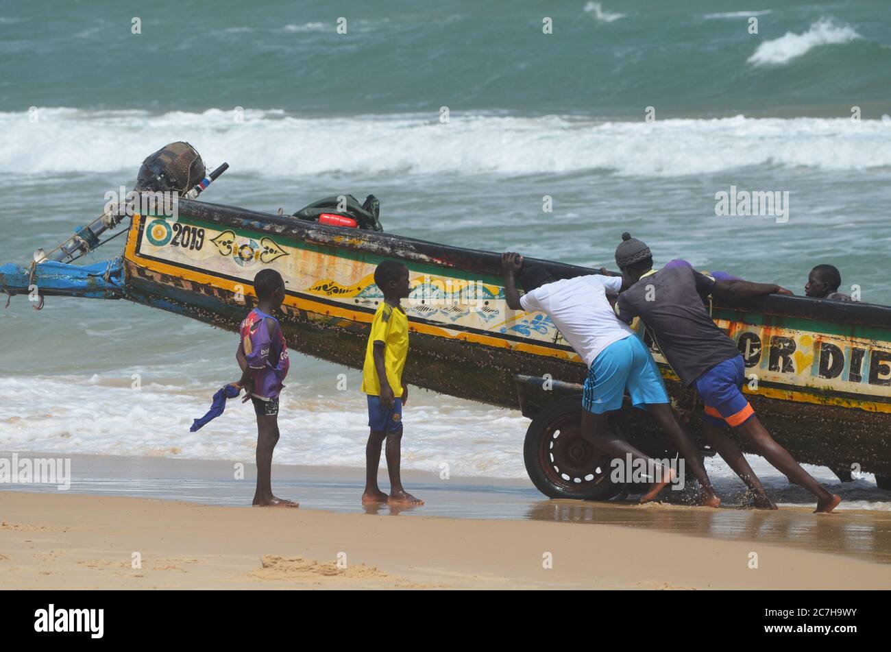 Artisanal fishermen pushing pirogues out of the water in Lompoul, Senegal Stock Photo