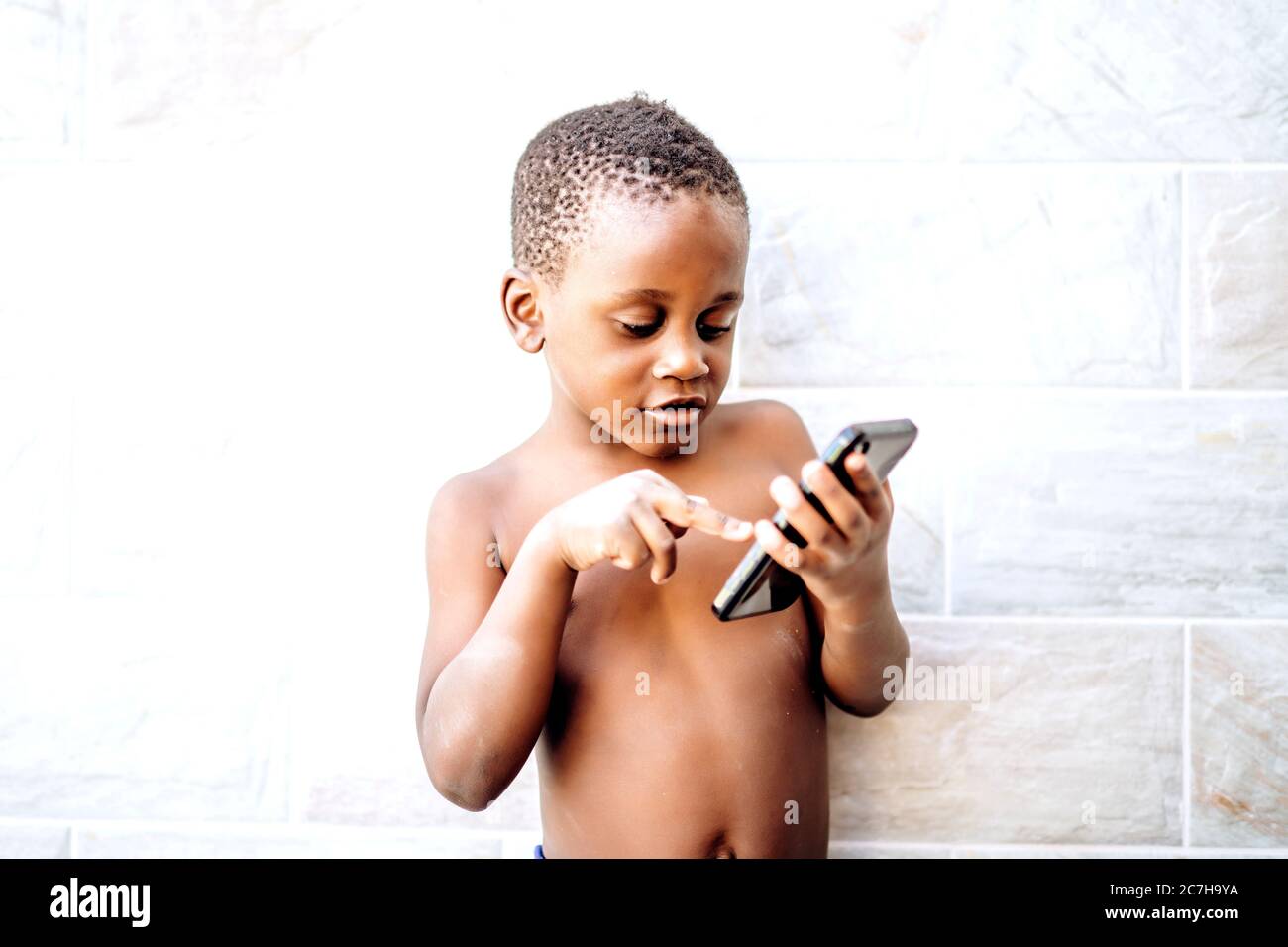 Nice african boy has fun using a mobile phone. Stock Photo