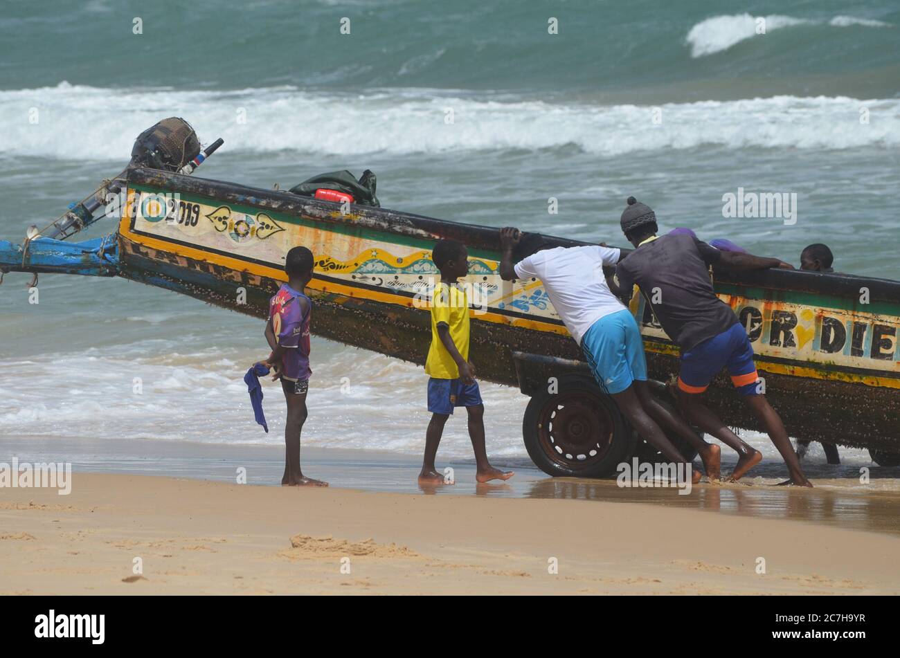 Artisanal fishermen pushing pirogues out of the water in Lompoul, Senegal Stock Photo