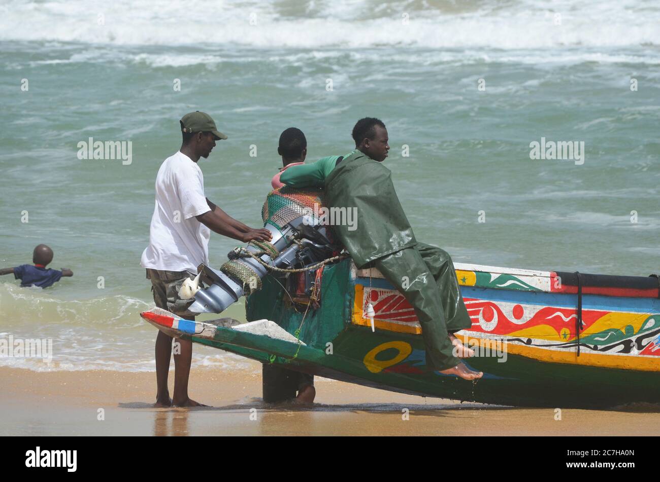 Artisanal fishermen pushing pirogues out of the water in Lompoul, Senegal Stock Photo