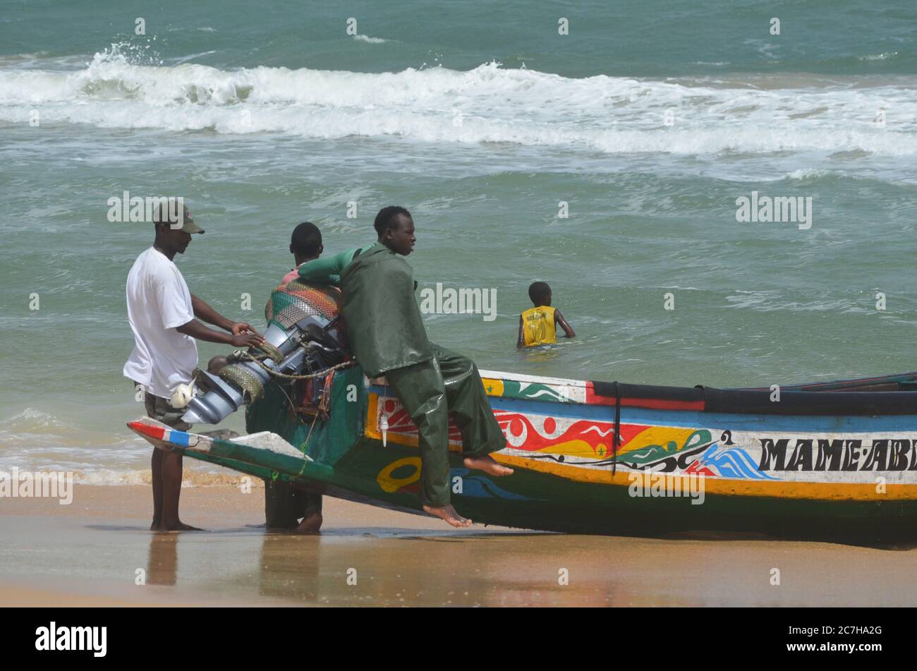 Artisanal fishermen pushing pirogues out of the water in Lompoul, Senegal Stock Photo