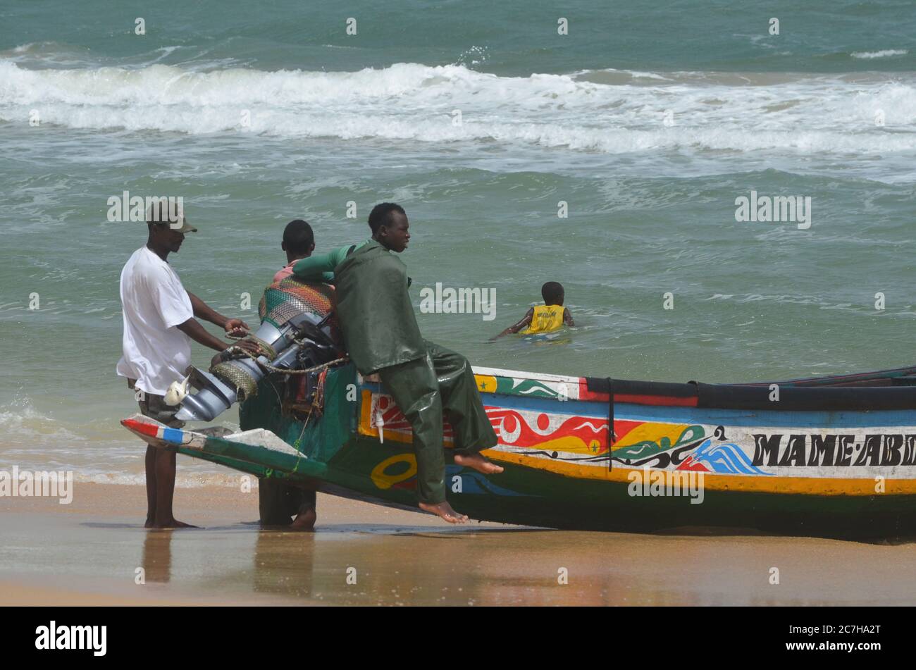 Artisanal fishermen pushing pirogues out of the water in Lompoul, Senegal Stock Photo