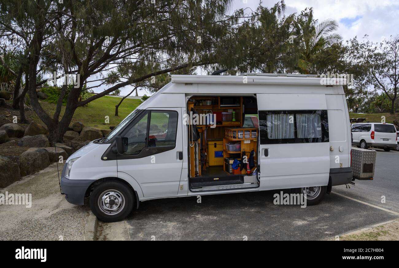 White compact van with household goods in it in a park surrounded by greenery Stock Photo