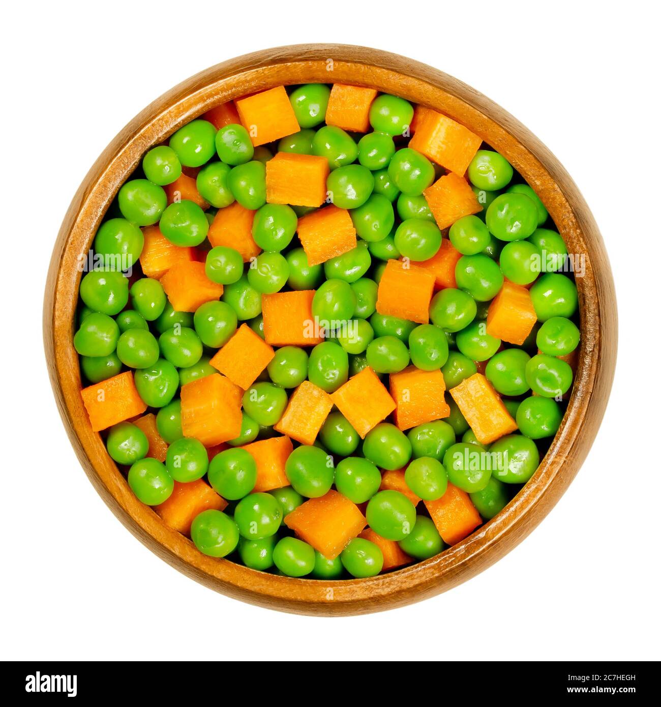 Green peas and carrot cubes in wooden bowl. Mixed vegetables. Seeds of pod fruit Pisum sativum and orange colored cubes of carrots, Daucus carota. Stock Photo