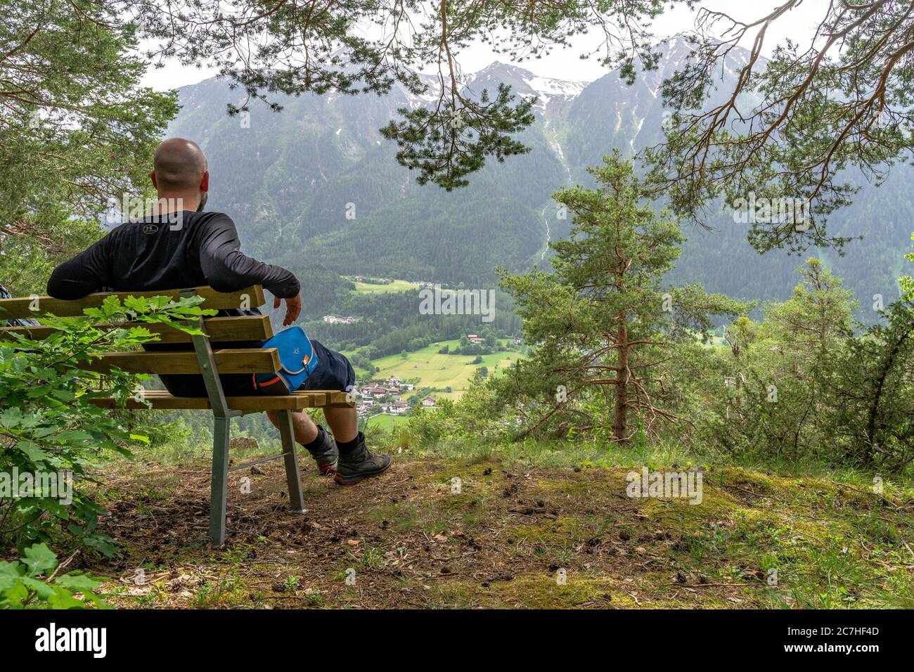 Europe, Austria, Tyrol, Ötztal Alps, Ötztal, hiker sits on a bench with a view of Sautens and the surrounding mountains Stock Photo